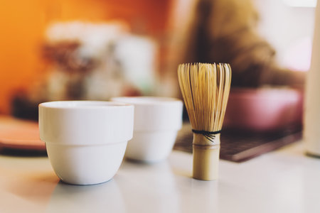 A set of two cups for the green matcha tea and a traditional bamboo whisk for whipping matcha powder. Tea making ceremony in an asian coffee shop. Healthy and tasty beverage. Vegetarian lifestyle.の写真素材