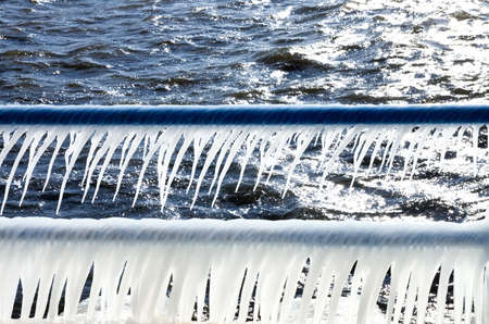 Spray from the cold January water form icicles on the railings of the Holland Harbor channel backlit from an afternoon sunの写真素材