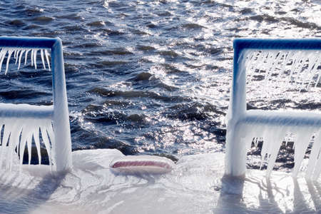 Spray from the cold January water form ice on the channel wall and fixtures of the Holland Harbor backlit from an afternoon sunの写真素材