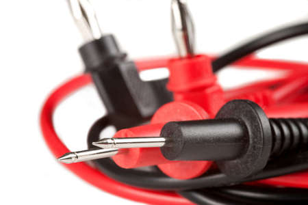 Pointed electrical test probes with red and black leads, banana plugs in background