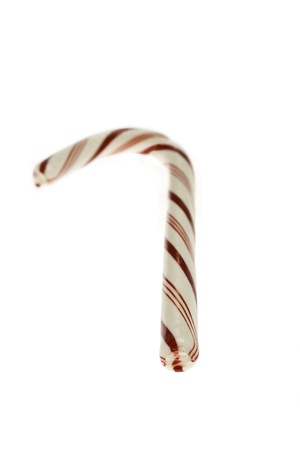 A traditional crooked white with red stripes candy cane with focus on the end and the hook in blurの写真素材
