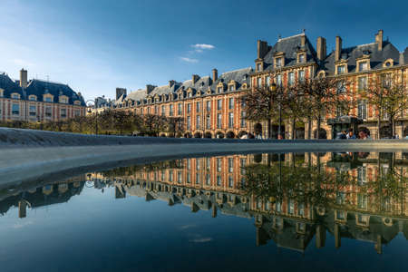 Paris, France - April 8, 2021: Nice view of Place des Vosges garden in Paris. Buildings reflected in the water of a fountainのeditorial素材