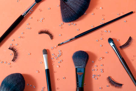 brushes for makeup of different sizes on a pastel background, accompanied by false eyelashes and small diamonds distributed by the set, top and close view,の写真素材
