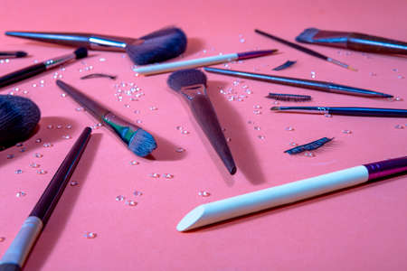 brushes for makeup of different sizes on a pastel background, accompanied by false eyelashes and small diamonds distributed by the set, top and close view,の写真素材
