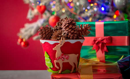 Pot decorated in red and green, with reindeer and pine full of pine-codes and in the background a...