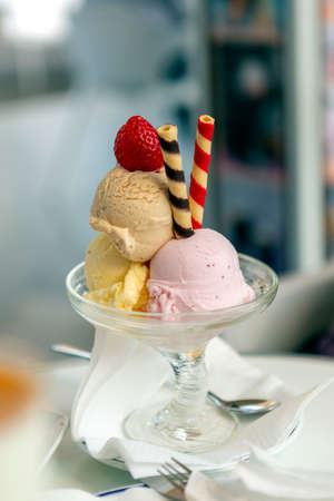 Cream ice cream with three flavors, accompanied by colorful spiral wafers, all presented in a...
