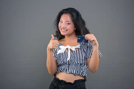 pretty young happy and smiling chinese girl showing credit card