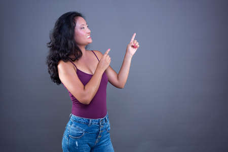 Young pretty long-haired brunette Chinese extending her hand to the side to show or indicate something.の写真素材