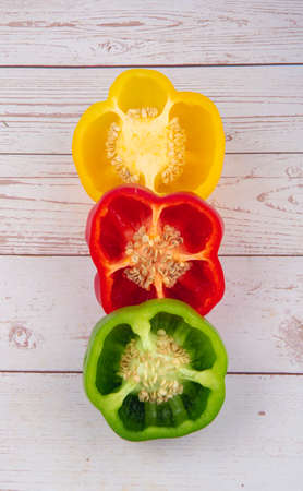Red, green, yellow peppers in half on wooden table viewed from above ..の写真素材