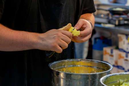 cook cutting potatoes into small pieces to make the typical Spanish meal, tortilla de patatas. (potato omelet)の写真素材