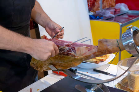 close up shot of professional slicer to carve slices of whole serrano ham with boneの写真素材