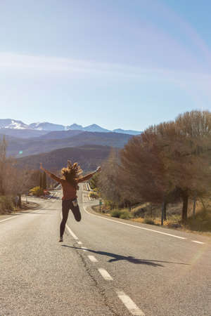 woman seen from behind jumping in the middle of a highwayの写真素材