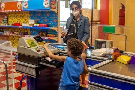 Boy playing a supermarket cashier with his motherの写真素材