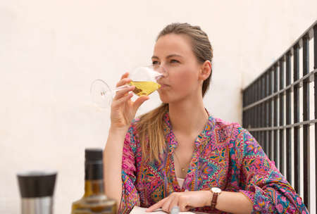 woman on terrace tasting a glass of white wineの写真素材