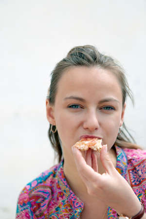 close-up of a pretty young woman biting a piece of toast in a bar terraceの写真素材