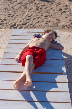 child sunbathing lying on a pool loungerの写真素材