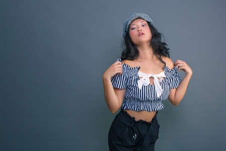 pretty young Chinese girl posing for the camera on a gray backgroundの写真素材