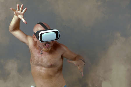 shirtless bald man in his fifties with virtual reality goggles playing