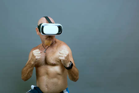 shirtless man in his fifties with virtual reality goggles playing a gameの写真素材