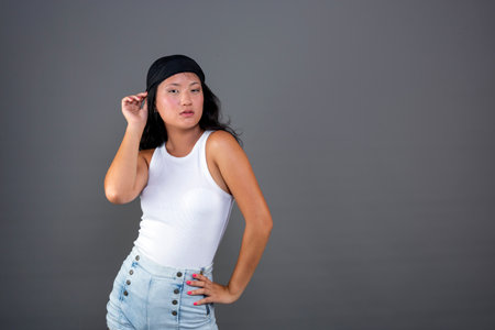 pretty young Chinese woman posing flirtatiously on gray backgroundの写真素材
