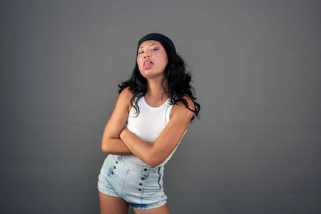 funny young chinese woman sticking out her tongue and making facesの写真素材