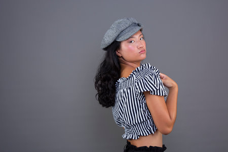Young Chinese girl posing for the camera on a gray backgroundの写真素材