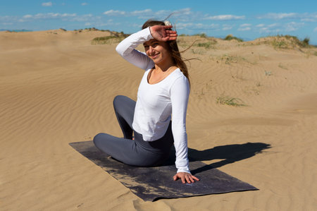 beautiful woman with yoga mat sitting on dunesの写真素材
