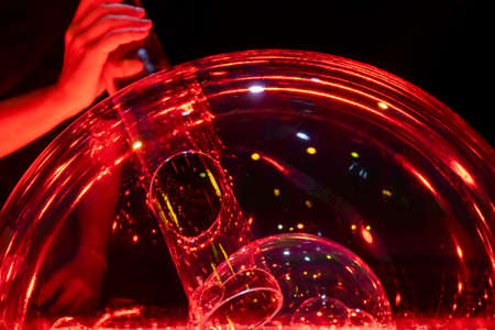 blowing double soap bubble made with a tube and illuminated in red creating an original effect.