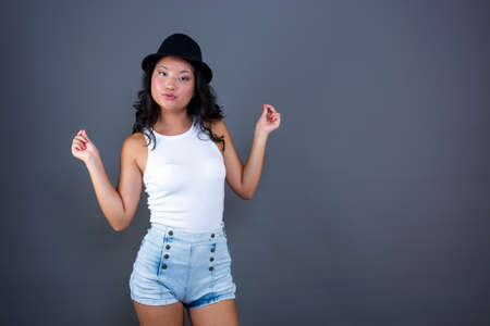 Young ethnic Asian woman posing in tank top, shorts and hat.の写真素材