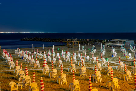view of the beach at night with closed beach umbrellas tables and chairs, mar del plata Argentinaの写真素材
