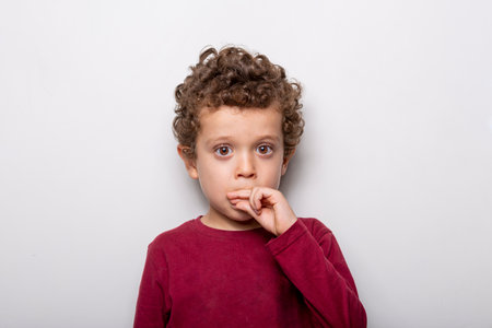 cute little boy with brown eyes and curly hair on a white backgroundの写真素材