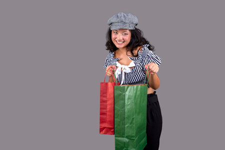 young ethnic asian girl with shopping bags isolated on gray backgroundの写真素材