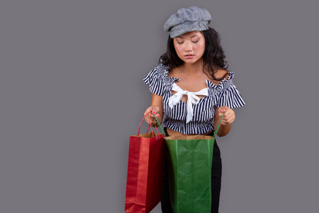 asian ethnic woman with shopping bags isolated on gray backgroundの写真素材