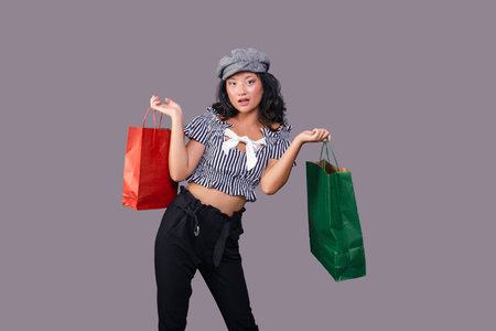 young ethnic asian girl with shopping bags isolated on gray backgroundの写真素材