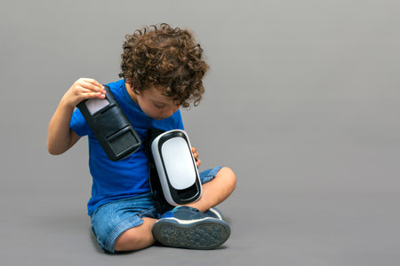 child with virtual reality goggles in his hands looking curiously at how they workの写真素材