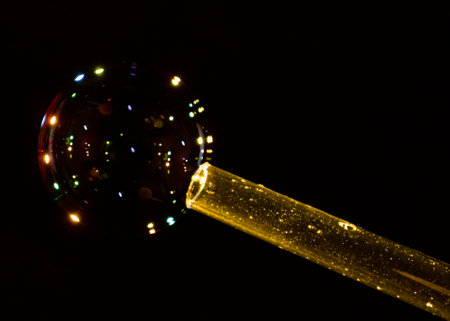colored lights reflected in soap bubble created through a transparent tubeの写真素材