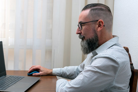 photo of hipster bearded man working with laptop computer at homeの写真素材
