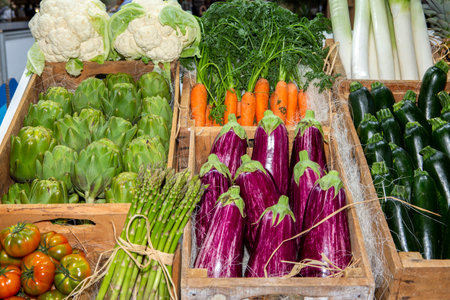 photo of vegetables in the market in wooden crates. tomato, cauliflower, cucumber, carrot, artichoke, eggplant etc.の写真素材