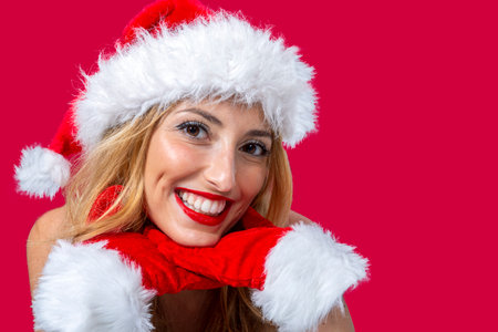 close-up of young woman with Santa Claus hat, wide smile resting her chin on her handsの写真素材