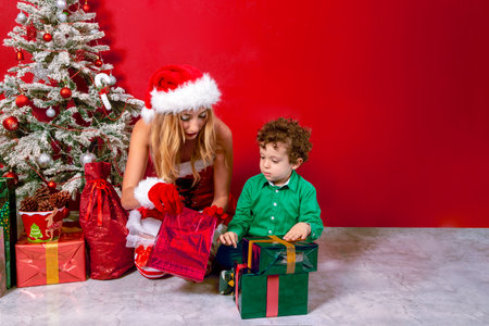 woman in Santa Claus costume next to child with Christmas presentsの写真素材