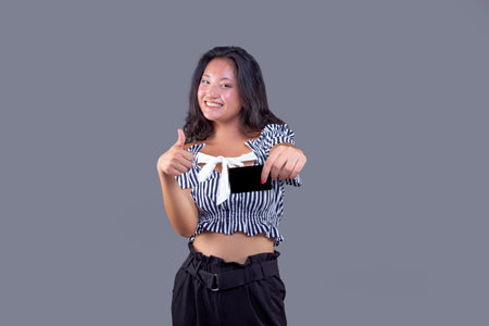 young woman showing card in her hand isolated from the backgroundの写真素材