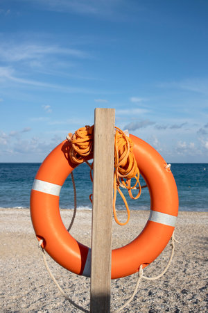 Orange lifebuoy on the beach with blue sky in background.の写真素材