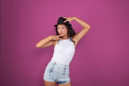 young woman with hat making cute face isolated from the backgroundの写真素材