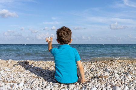 Feeling the ocean breeze and the excitement of throwing stones into the waterの写真素材