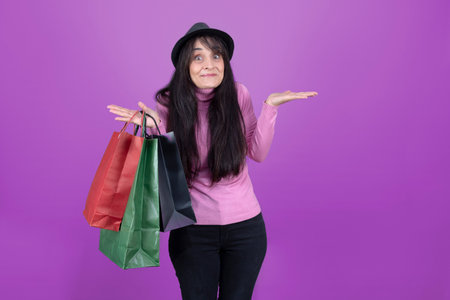 The friendly woman with paper shopping bags, pink sweater, and black hat isolated from the background.の写真素材