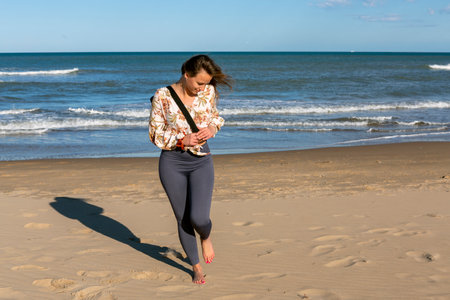 pretty woman walking barefoot on the beach with mat slung over her shoulderの写真素材