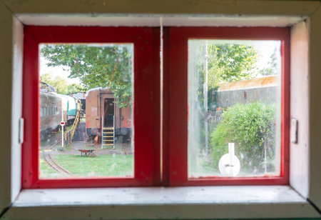 old wooden window overlooking abandoned trainsの写真素材