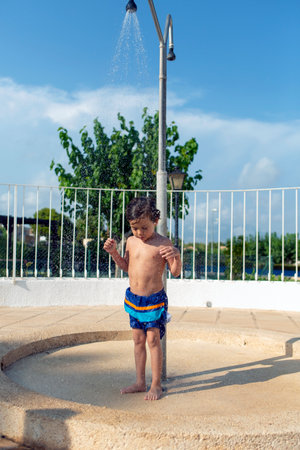 funny child cooling off in the shower of the swimming poolの写真素材