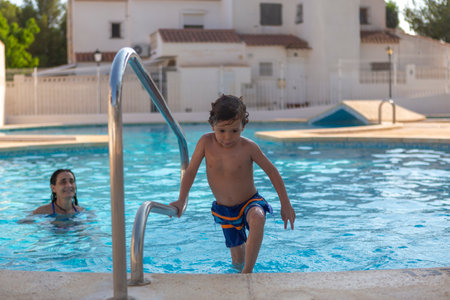 boy getting out of the pool by the stairsの写真素材