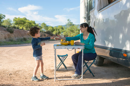 mother and son at camping table next to motorhomeの写真素材